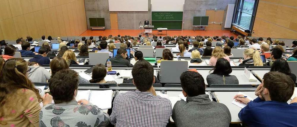 In einem Hörsaal sitzen Studierende, vorne steht ein Hochschullehrer.