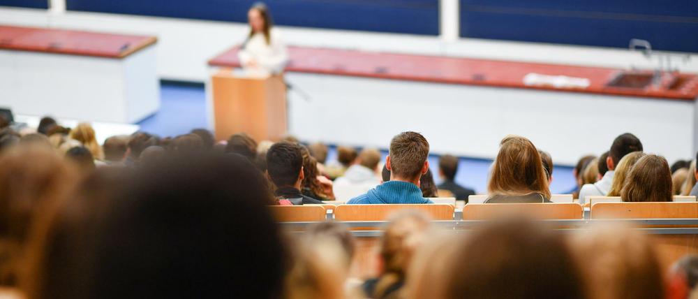Eine Dozentin spricht in einem Hörsaal vor Studierenden.