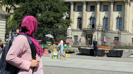 Eine Frau mit Kopftuch geht an der Humboldt-Universität an der Straße Unter den Linden in Berlin vorbei. 