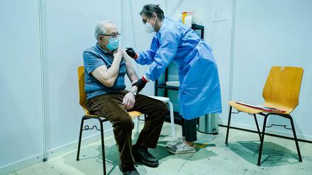 Ein Mann lässt sich im Impfzentrum Kaiserslautern von einer Mitarbeiterin impfen.