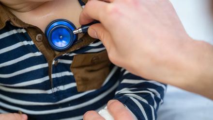 Ein Kinderarzt untersucht ein Kind mit einem Stethoskop.