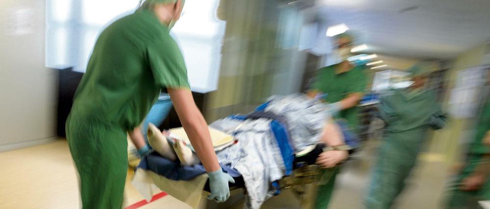 Ein Ärzteteam schiebt einen Patienten auf einer Krankentrage durch einen Raum.