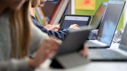 Schülerinnen arbeiten in einem Klassenraum an Tablets und Laptops.