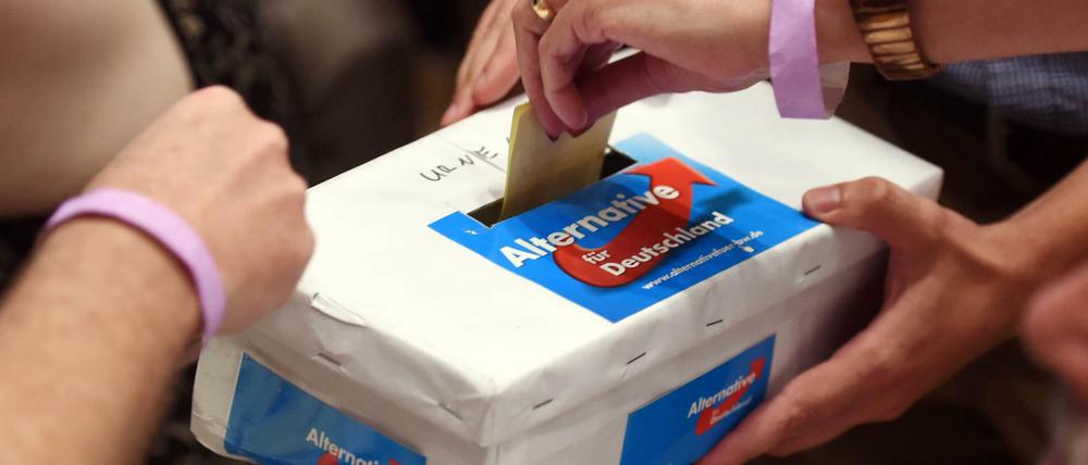 Stimmzettel werden in einen Karton mit dem AfD-Logo gesteckt.
