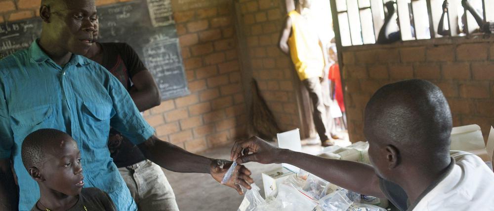 Hoffnung. Dieser Mann erhält Medizin, um seinen malariakranken Sohn zu behandeln. Eine Impfung könnte die Zahl der Infektionen verringern. 