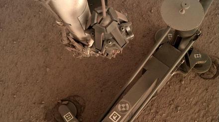 Foto des Marsmaulwurfs, aufgenommen von einer Kamera am Roboterarm der NASA-Sonde "Insight". An den Standfüßen sieht man, wie sich das Gehäuse durch das Hämmern verschoben hat. Die Rammsonde selbst ist rechts oben.