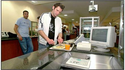Ein Student steht mit seinem Essenstablett an der Mensa-Kasse.