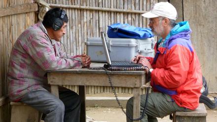 Hörtest. Das Foto zeigt wie ein Wissenschaftler einem Mitglied des am Amazonas lebenden Tsimane-Volkes westliche Musik über vom Laptop über Kopfhörer vorspielt. 