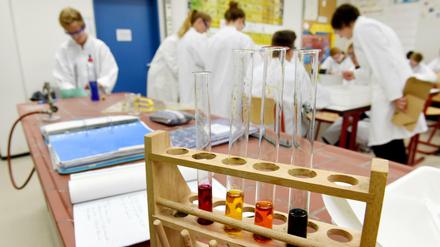 Zehntklässler im Chemieunterricht an einem Gymnasium in Baden-Württemberg. Im Vordergrund stehen Reagenzgläser in einem Gestell.