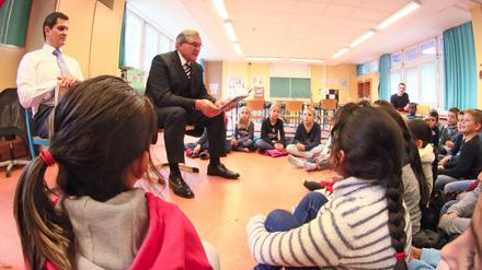 Kinder sitzen beim Vorlesetag im Halbkreis auf dem Boden und hören zu.