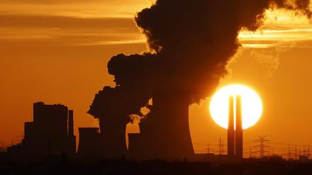 Das Kohlekraftwerk Niederaußem in Nordrhein-Westfalen zeichnet sich gegen die untergehende Sonne ab.
