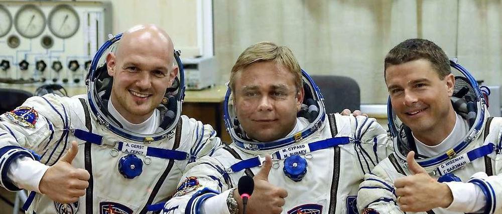 Posing für die Kameras: Vor dem Abflug geben die drei Astronauten noch eine Pressekonferenz - hinter einer Glasscheibe. 