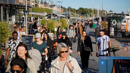Schönes Wetter und viel los: Menschen laufen an einem sonnigen Tag durch Stockholm.