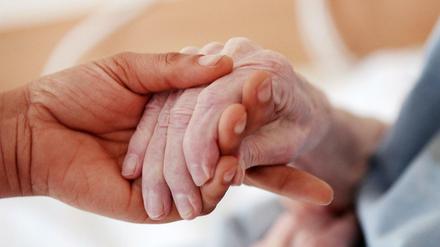 Eine Pflegerin hält einem Altenheim die Hand einer Bewohnerin (Symbolbild). 
