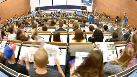 Studierende sitzen in einem Hörsaal und blicken nach vorne.