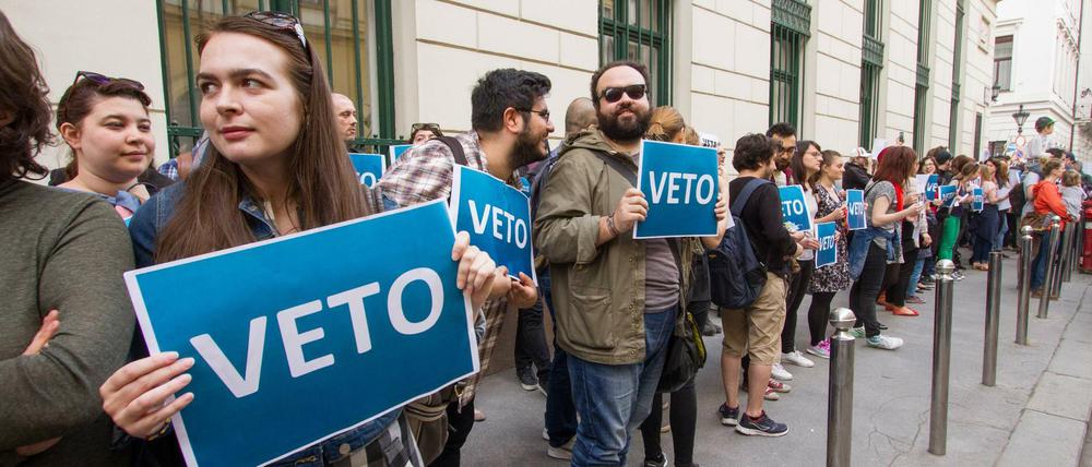 Menschen stehen in einer Kette und halten Schilder mit der Aufschrift Veto hoch.