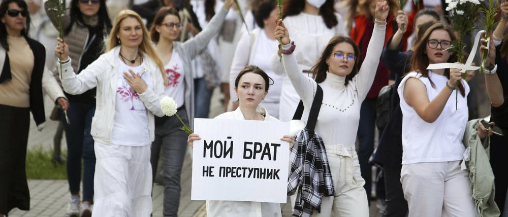 Belarussische Frauen halten bei einem Protest weiße Blumensträuße in die Luft, um ihre Solidarität mit den politischen Gefangenen auszudrücken.