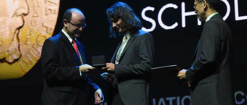 Nicht um den Hals, sondern in die Hand: Peter Scholze bekommt seine Medaille nach Mathematikerart.