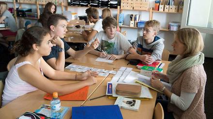 Schüler sitzen in der Klasse an einem Tisch und machen Gruppenarbeit.