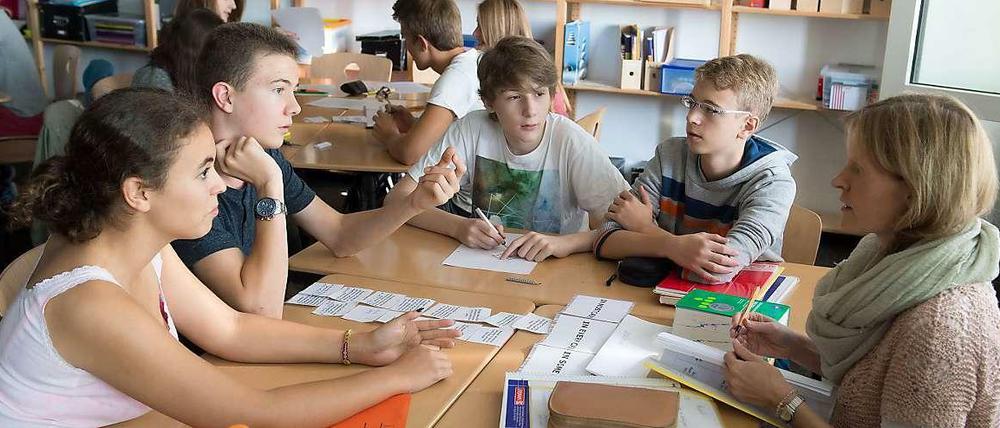 Schüler sitzen in der Klasse an einem Tisch und machen Gruppenarbeit.