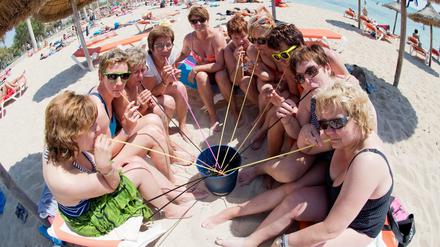 Deutsche Touristinnen trinken aus einem Eimer am Strand auf Mallorca.