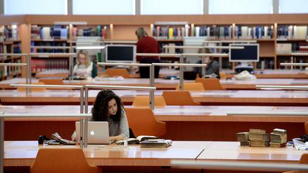 Eine junge Wissenschaftlerin sitzt in einem Lesesaal der Staatsbibliothek zu Berlin an ihrem Laptop.