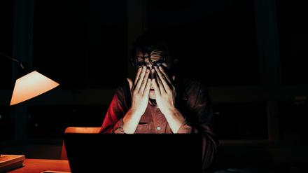 Ein Student sitzt abends vor seinem Laptop und reibt sich die Augen.