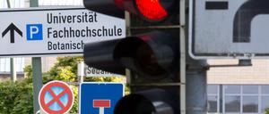 Eine rote Ampel und Verkehrsschilder für "Sackgasse" und "absolutes Halteverbot" sind am 28.07.2015 in Osnabrück (Niedersachsen) vor einem Hinweis auf Universität und Fachochschule zu sehen.