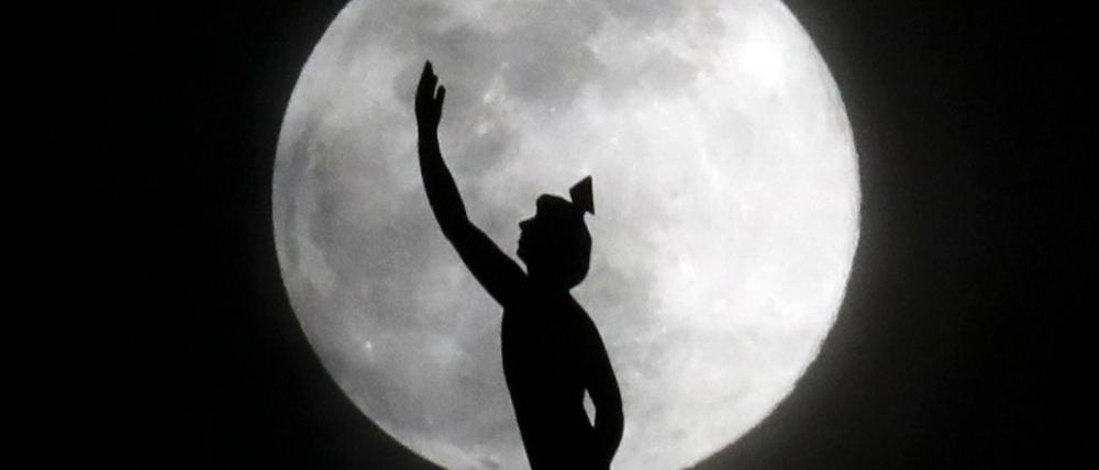 Der Mond ist hinter einer Statue auf der Spitze eines Hotelturms in Nashville in den USA zu sehen.