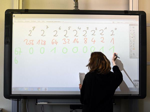 Eine Lehrerin schreibt Mathematikaufgaben an eine interaktive Tafel.