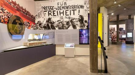 Auf Wandbildern sind ein Blick in die Volkskammer der DDR sowie eine Demonstration für "Freiheit" zu sehen.