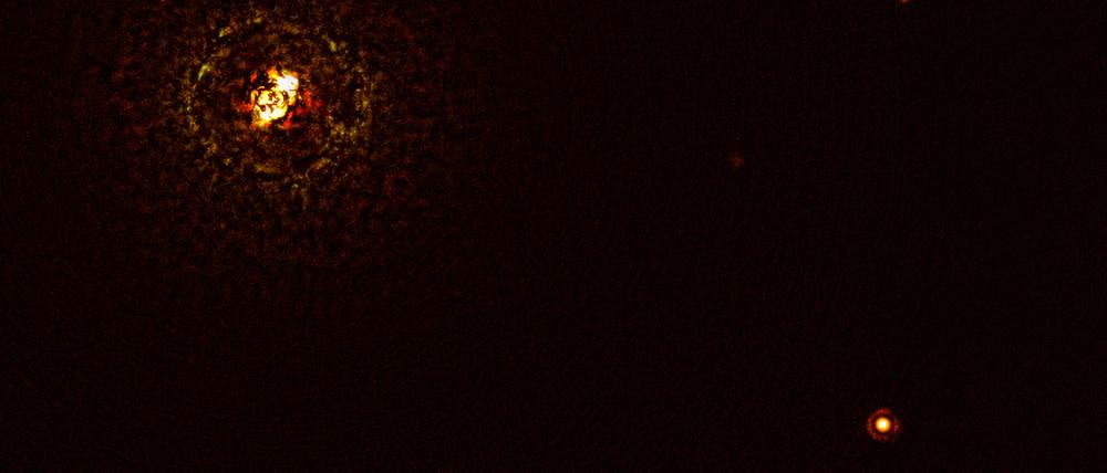 Der Doppelstern b Centauri (links oben) ist sechs mal so massiv wie die Sonne und so heiß, dass es nach gängiger Theorie zur Planetenentstehung eigentlich gar keinen Planeten in seiner Nähe (rechts unten) geben dürfte.