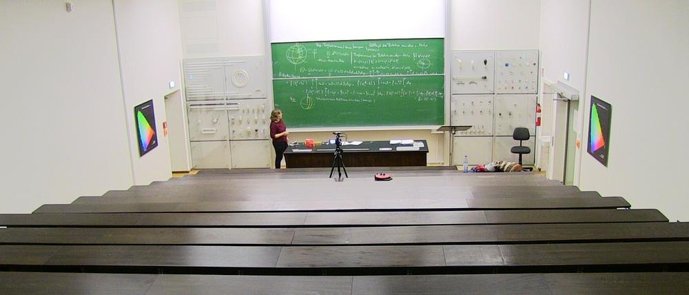 Eine Mathematikdozentin hält ihre Vorlesung in einem leeren Hörsaal und wird dabei gefilmt.