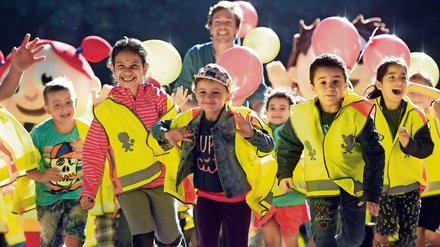 Kinder in gelben Rettungswesten laufen lachend in Richtung Kamera.