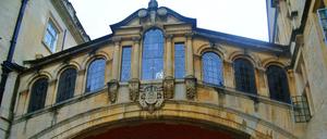 Auf dem Campus der Universität Oxford sind Passanten unter einer Passage zwischen zwei Gebäuden zu sehen.