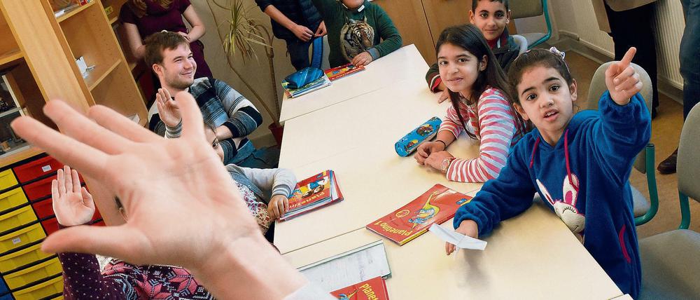 Kinder sitzen in einem Klassenraum vor Schulbüchern.