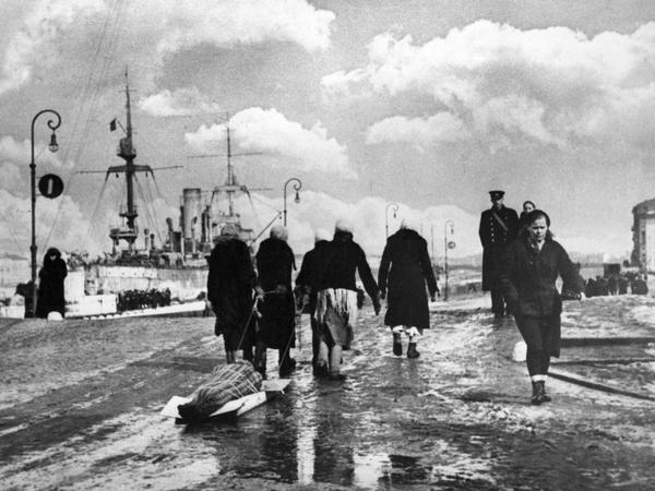 In Leningrad ziehen Frauen während der deutschen Blockade im Zweiten Weltkrieg eine verhüllte Leiche zum Friedhof.